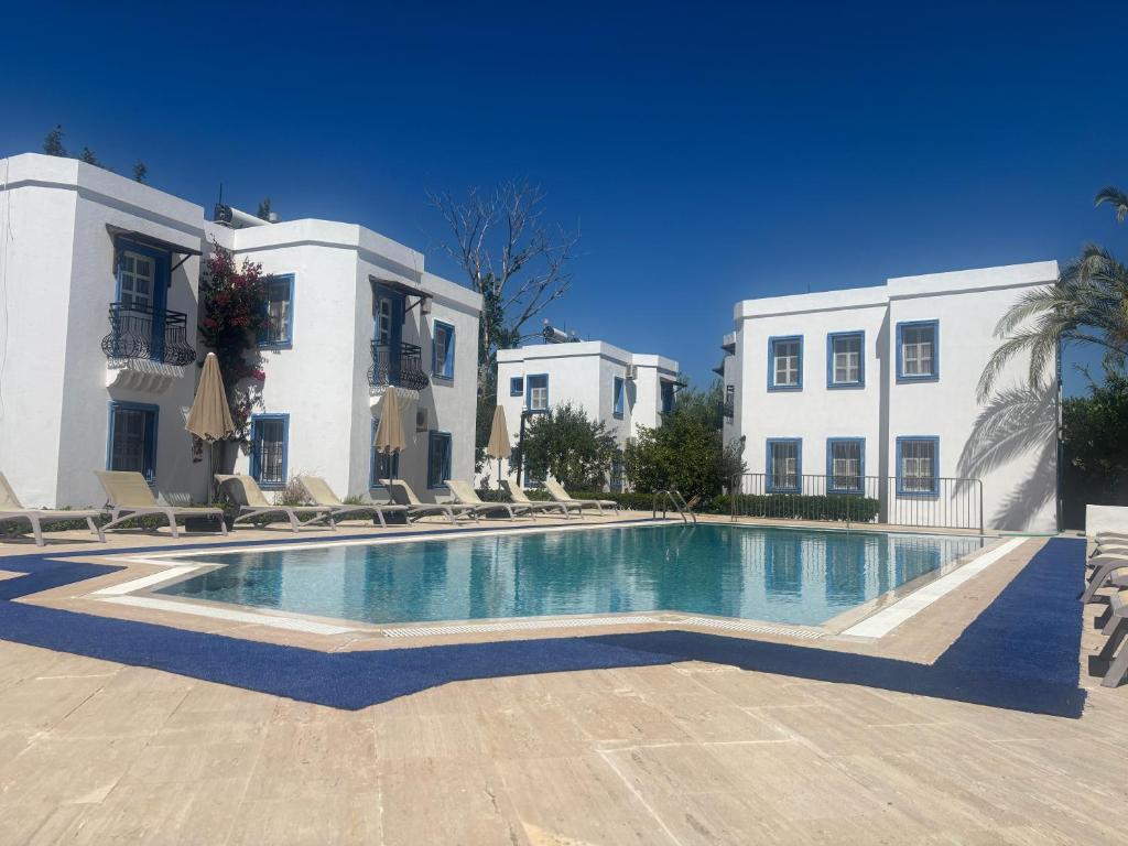 a swimming pool in front of two white buildings at Ege Apartments in Yalıkavak
