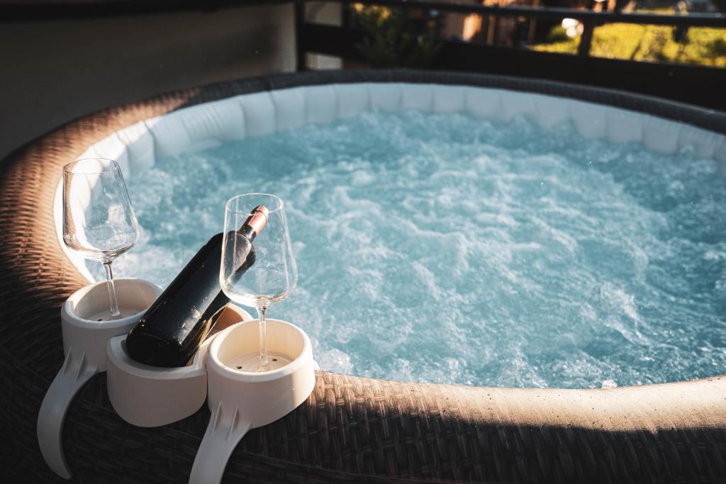 a hot tub with two glasses and a bottle of wine at Riverside Home Laura in Karlovac