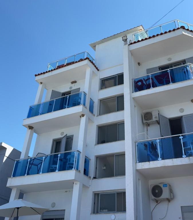 a white apartment building with blue balconies at Vila Kalluci in Borsh
