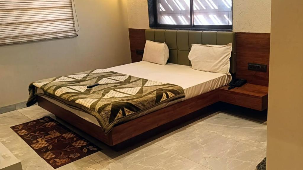 a bedroom with a bed in a room with a window at Abhilashaa Inn in Pachmarhī