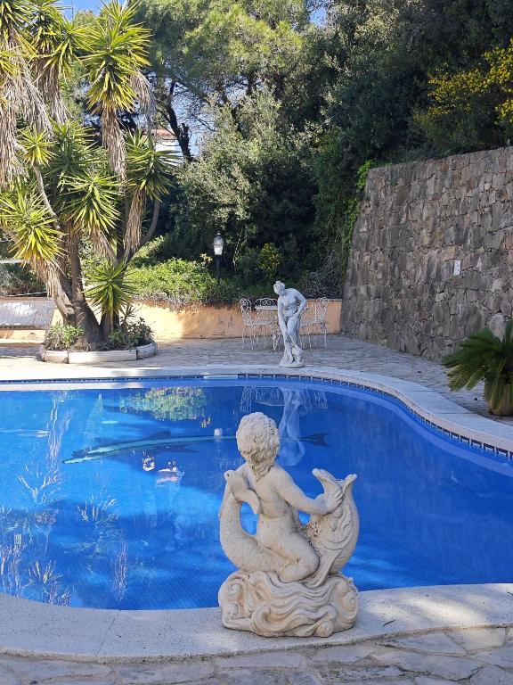 a statue of a mermaid sitting next to a swimming pool at Villa Serra Brava mt Gemeinschatspool, 3 Apartments in Lloret de Mar