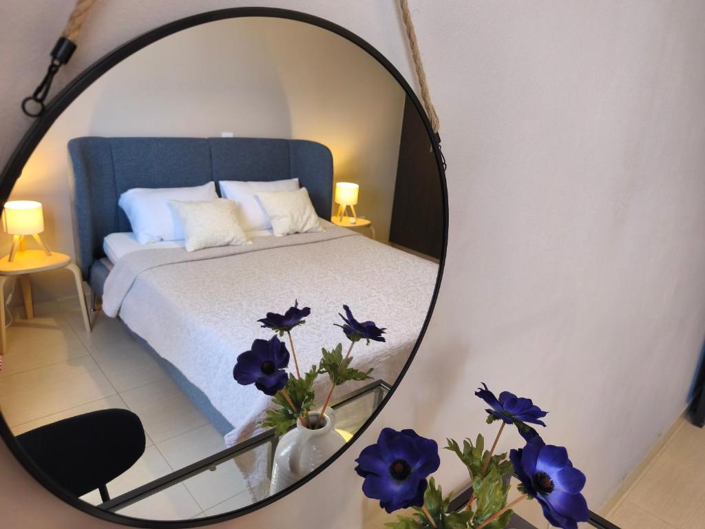 a mirror reflecting a bedroom with a bed and blue flowers at Michelle Mediterranean Suites in Meneou