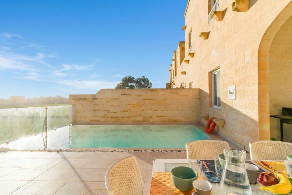 a patio with a table and chairs and a swimming pool at Inni Gozitan Farmhouse Private Pool- Happy Rentals in Santu Pietru