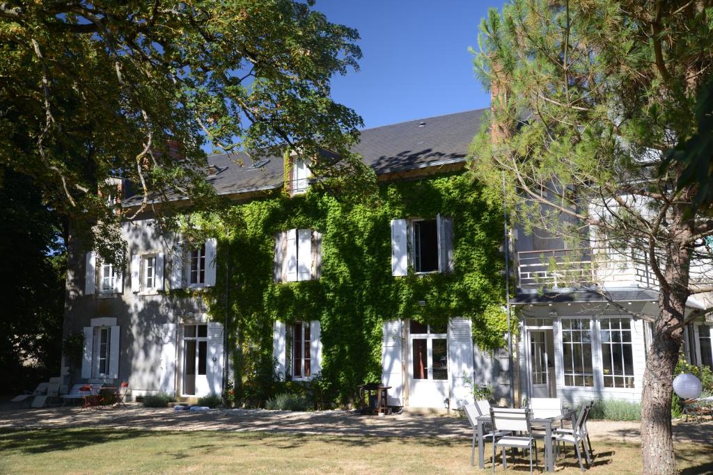 an ivy covered house with chairs and a tree at Domaine de Treuillaud in Villers-les-Ormes