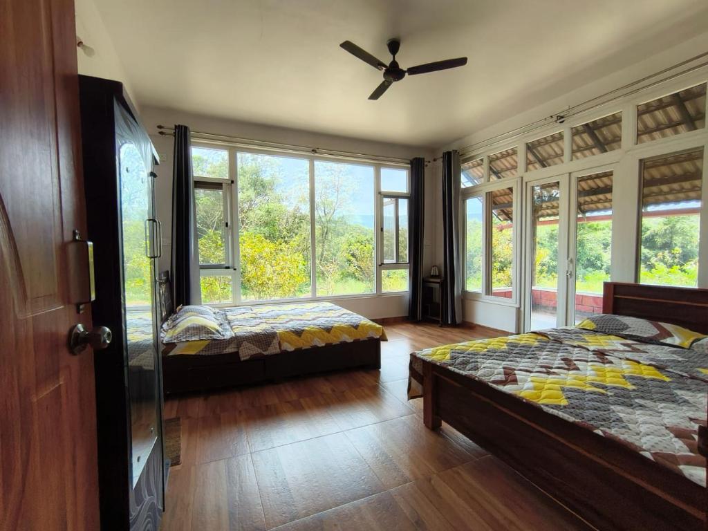 a bedroom with two beds and a ceiling fan at Tayra - The Glass Villa in Somvārpet