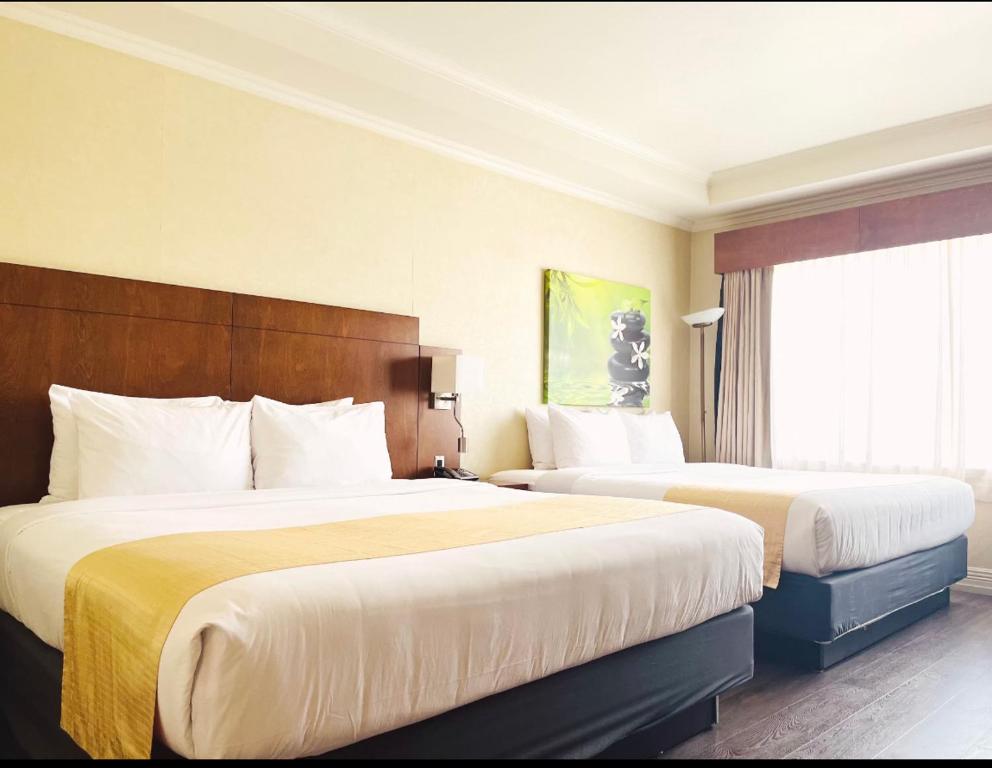 a hotel room with two beds and a window at Hotel & Suites Le Dauphin Drummondville in Drummondville