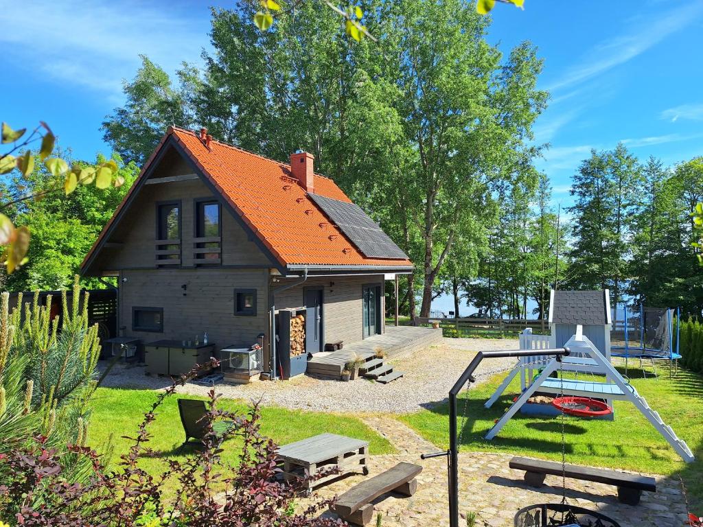a small house with an orange roof and a playground at Mazurska Widokówka in Węgorzewo