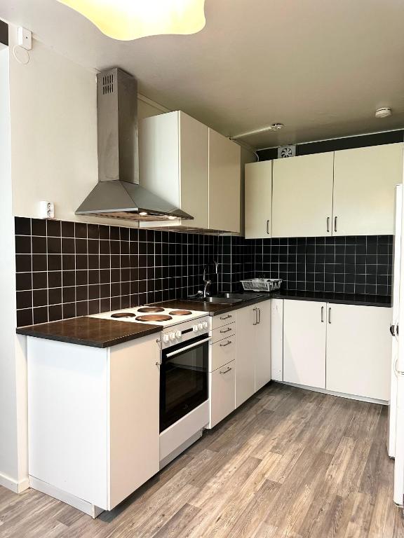 a kitchen with white cabinets and a stove top oven at Lägenhet Svängsta in Svängsta