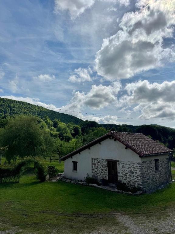 a small white building in a field with a hill at Gîte de Rille in Castelnau-Durban