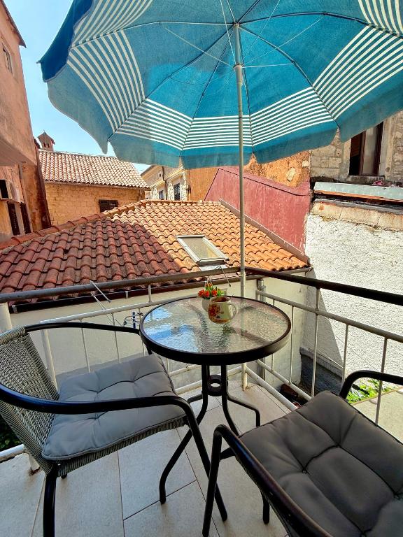 a table and chairs on a balcony with an umbrella at Majka 2 Apartments in Kotor