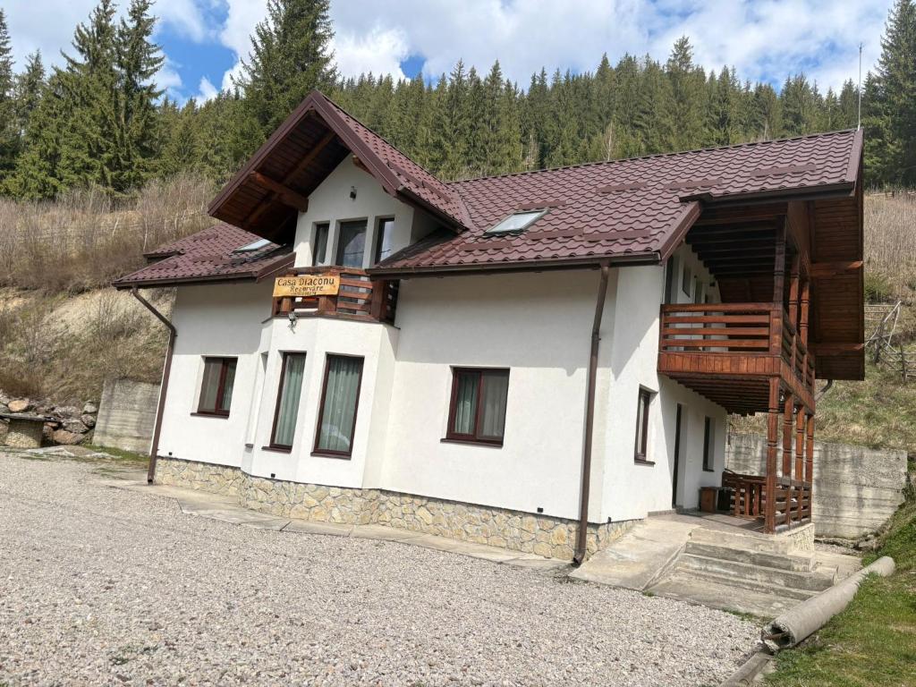 a white house with a brown roof at Casa Diaconu in Fundu Moldovei