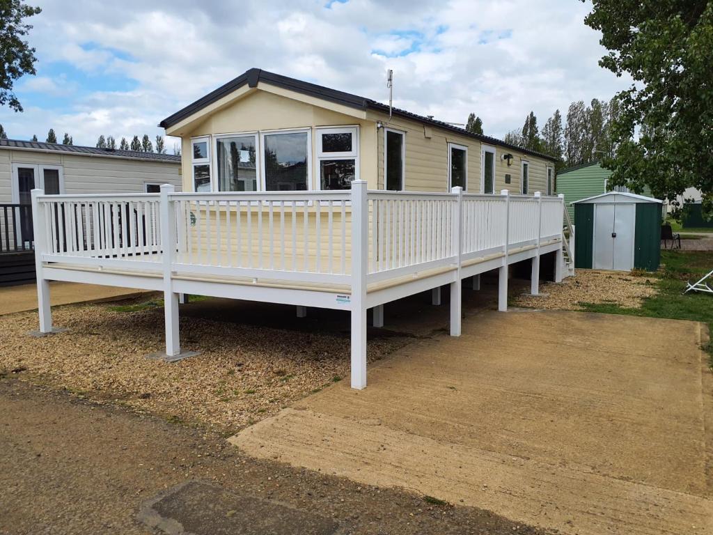 a house with a white porch and a white railing at LuLu's Lodge, Billing Aquadrome in Northampton