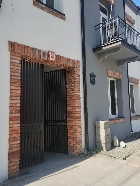 a brick building with a gate and a balcony at Apartament rodzinny SAKURA in Jędrzejów