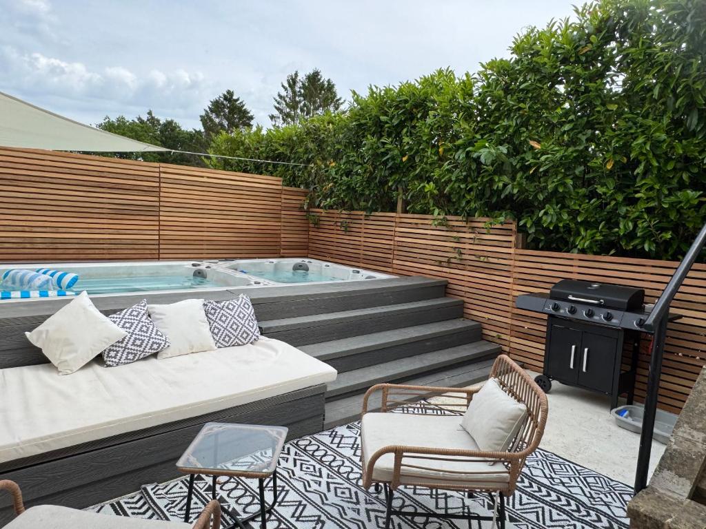 a patio with a hot tub and chairs and a grill at Little Rozel in East Grinstead