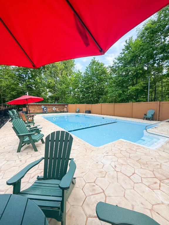 a pool with two chairs and a red umbrella at Northern Acres in Lake George