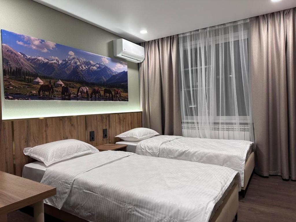a hotel room with two beds and a painting on the wall at GuestHouse-Medeu in Almaty