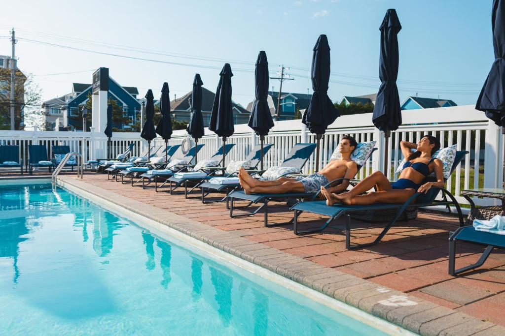 a group of people sitting on lounge chairs by a pool at Oceana By The Sea in Point Pleasant Beach