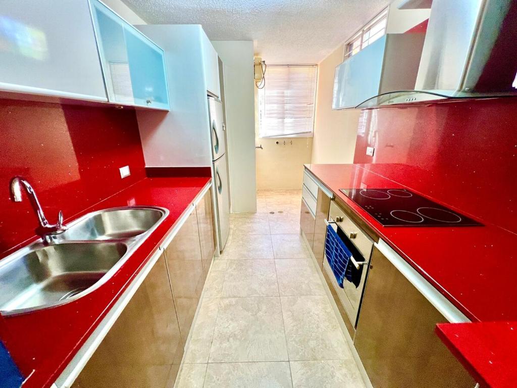 a red kitchen with a sink and a stove at Coral Suite Excellent location in Porlamar