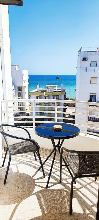 a table and two chairs on a balcony with the ocean at Appartement PRIMAVERA in Armação de Pêra