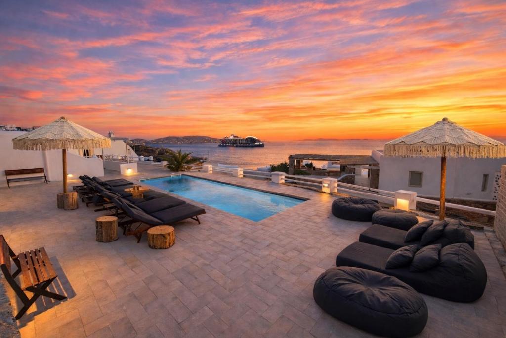 a villa with a swimming pool and a sunset at With-inn Mykonos Suites in Tourlos