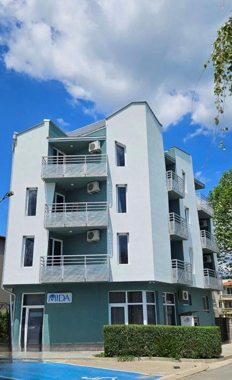 a tall white building with a pool in front of it at Hotel Mida in Obzor