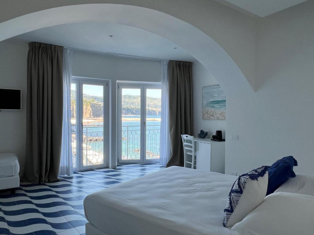 a bedroom with a white bed and a balcony at Metasuites Beach in Meta