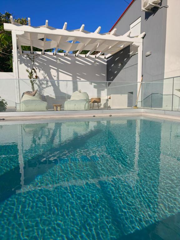 a swimming pool in front of a house with a pergola at Astre&Jeanne suites in Sozopoli