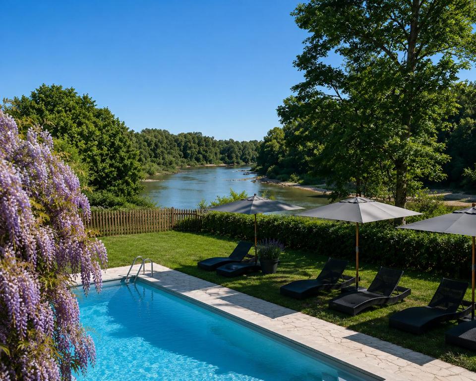a swimming pool with chairs and umbrellas next to a river at Le Clos des Berges de l'Ain in Charnoz