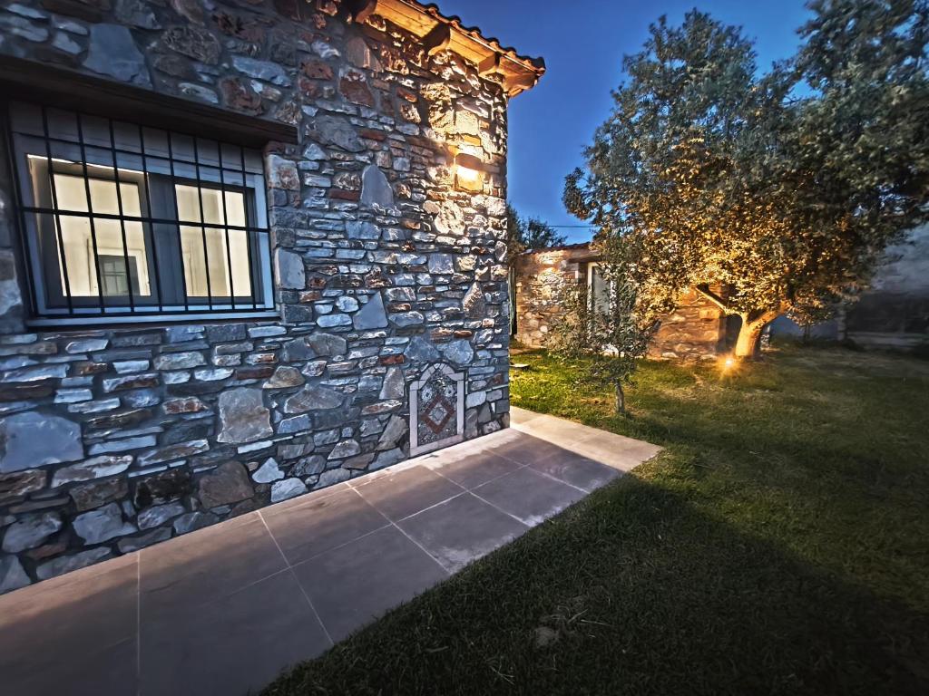 a stone house with a stone wall and a tree at KONSTANTINOS Luxury Living in Ofrínion