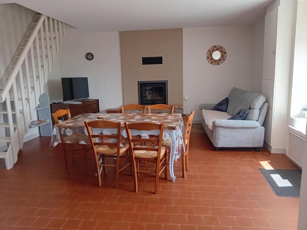 a dining room with a table and chairs and a couch at Gite de la haie portée in Lignieres-Orgeres