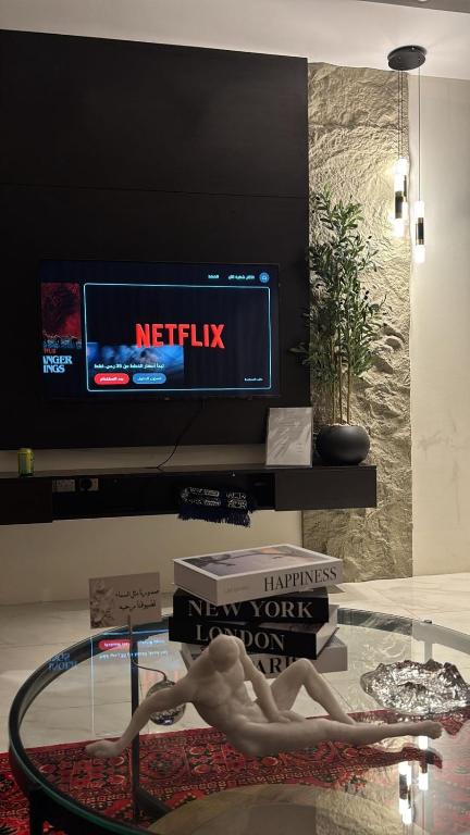 a room with a glass table with a woman sitting on a table with books at نزل سوم in Hail