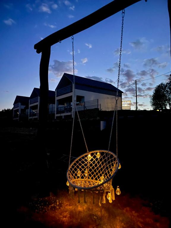 a swing in a yard with a house in the background at Domek Na Wzgórzu Roztocze in Majdan Abramowski