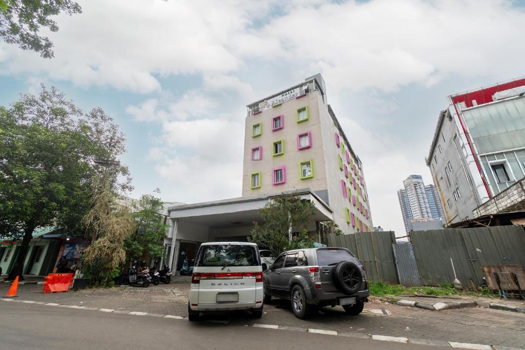 a car parked in front of a pink building at Hotel Aleander By ARBA in Jakarta