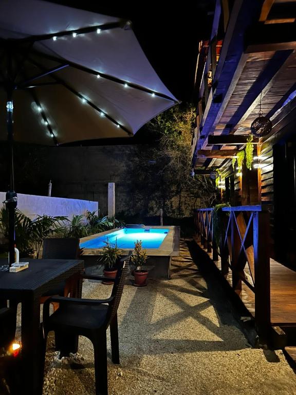 eine Terrasse mit Pool, Tischen und Sonnenschirm in der Unterkunft Cabañas Alebrije in Celestún