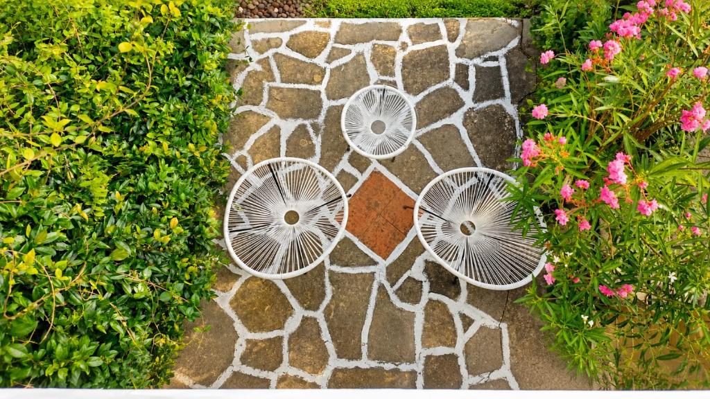 a garden with three white chairs on a stone path at Siviri Sea & Forest-Cozy Apartment with Garden & Nature Views in Siviri