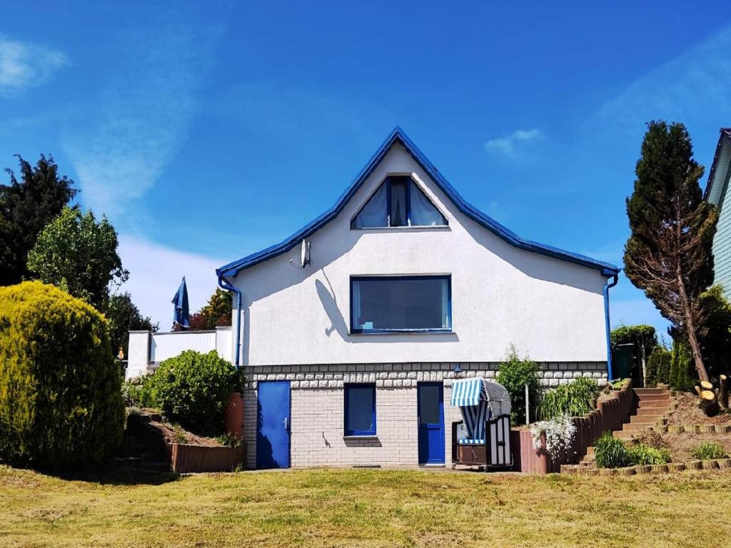 a white house with blue doors and a lawn at Wunderschönes Ferienhaus am Schilfufer in Barth in Barth