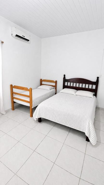 two beds in a room with a tiled floor at Estádia aconchegante! in Vilhena
