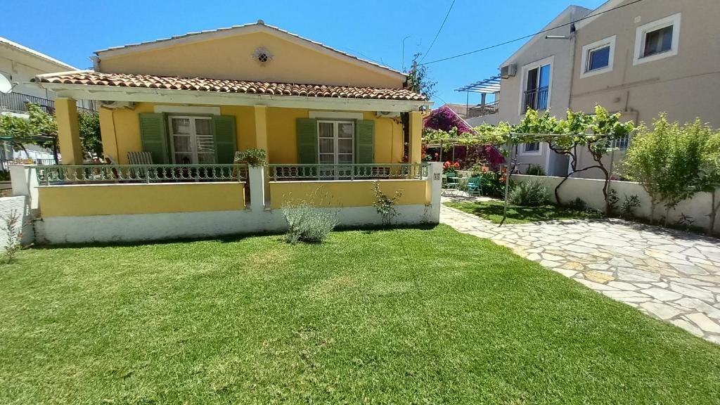 a small yellow house with a green yard at Kipos Apartments in Kassiopi