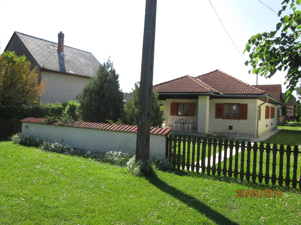 ein Haus mit einem Zaun vor einem Hof in der Unterkunft Fenyves Vendégház in Balatonfenyves
