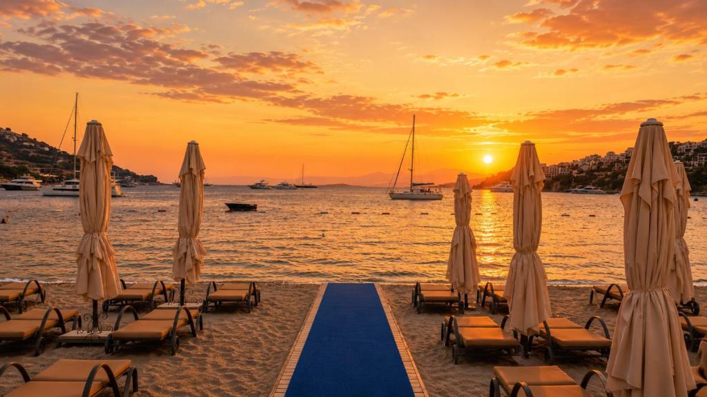 a beach with chairs and umbrellas at sunset at Mercans Bodrum Beach Hotel in Bodrum City