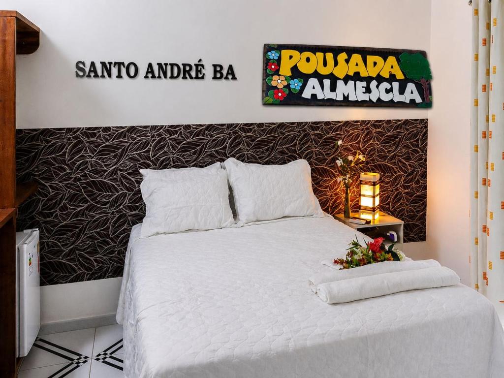 a bedroom with a white bed with a sign on the wall at Pousada & Restaurante Almescla in Santa Cruz Cabrália