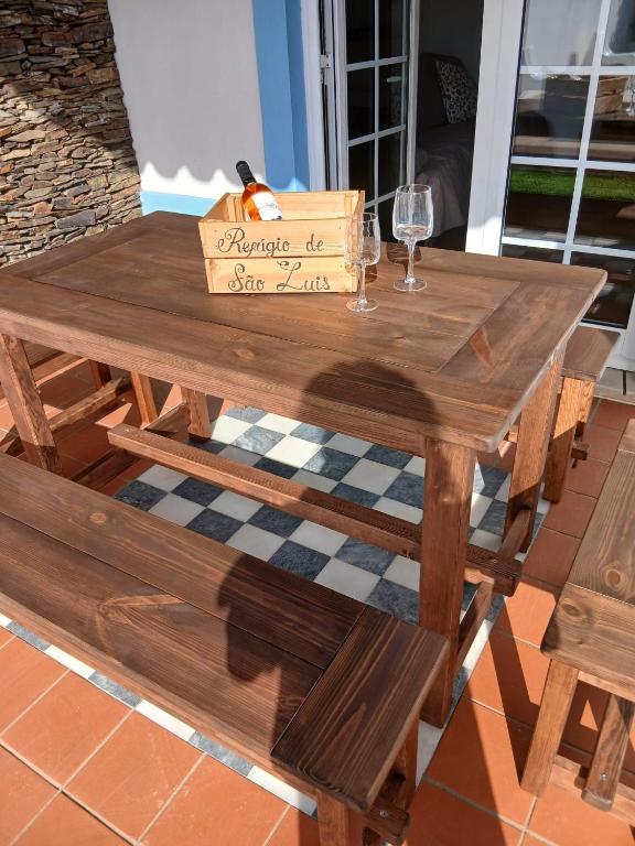 a wooden table with a box and a glass of wine at Refugio de São Luis in São Luis
