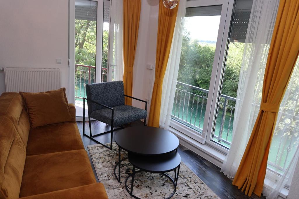 a living room with a couch and a chair and windows at Apartments and Rooms Villa Majestic in Bihać