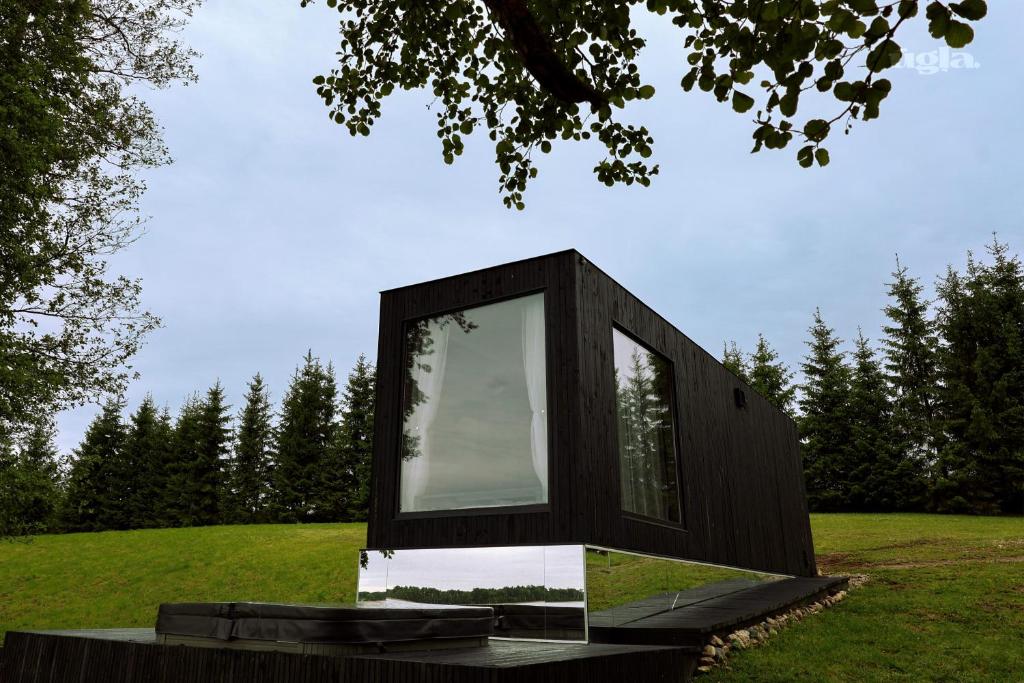 ein schwarzes Haus mit einem Fenster auf ein Feld in der Unterkunft Ūgļa in Puša