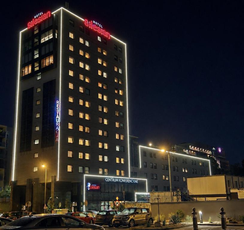 a tall building at night with cars parked in a parking lot at Great Polonia Silesian Economy Hotel in Katowice