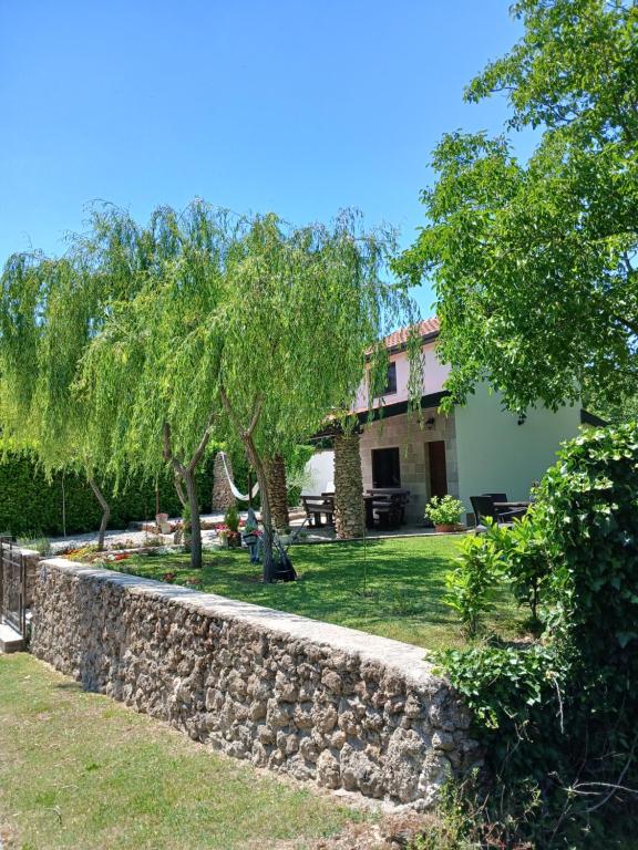 a stone retaining wall in front of a house at Kuća za odmor Buk in Čapljina