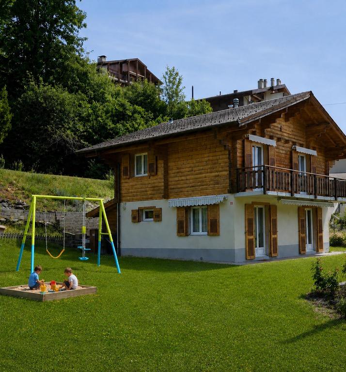 two children playing on a playground in front of a house at Chez Aless in Ovronnaz
