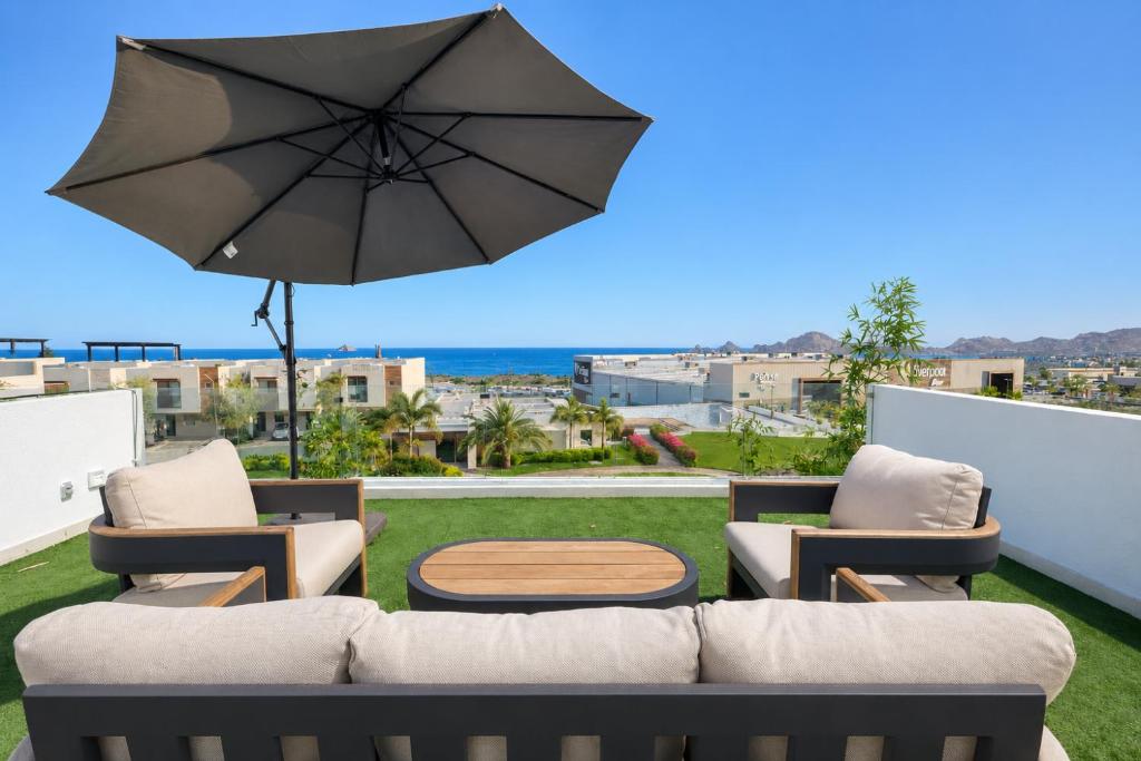 a patio with a couch and a table and an umbrella at Casa Vista 133 in Cabo San Lucas