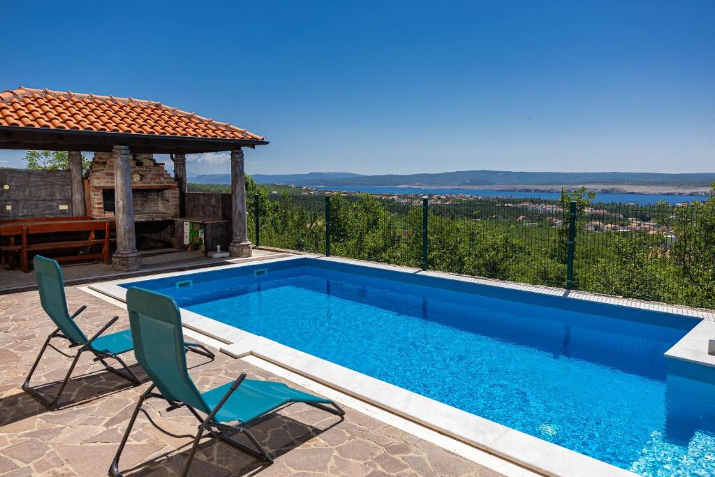 a swimming pool with two chairs and a gazebo at Apartment Panorama in Jadranovo