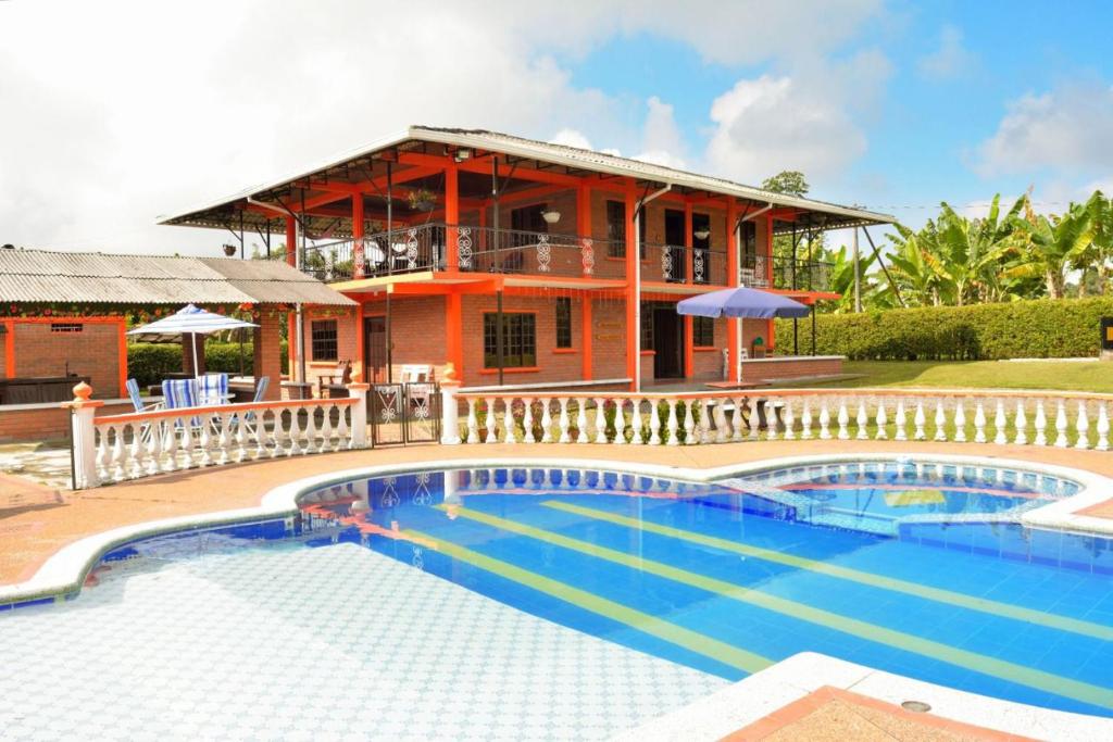 a house with a swimming pool in front of a building at Finca Hotel Montebello in Quimbaya